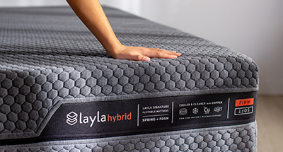 Hand pressing down on hybrid mattress