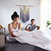 A couple sitting on a mattress with a white comforter