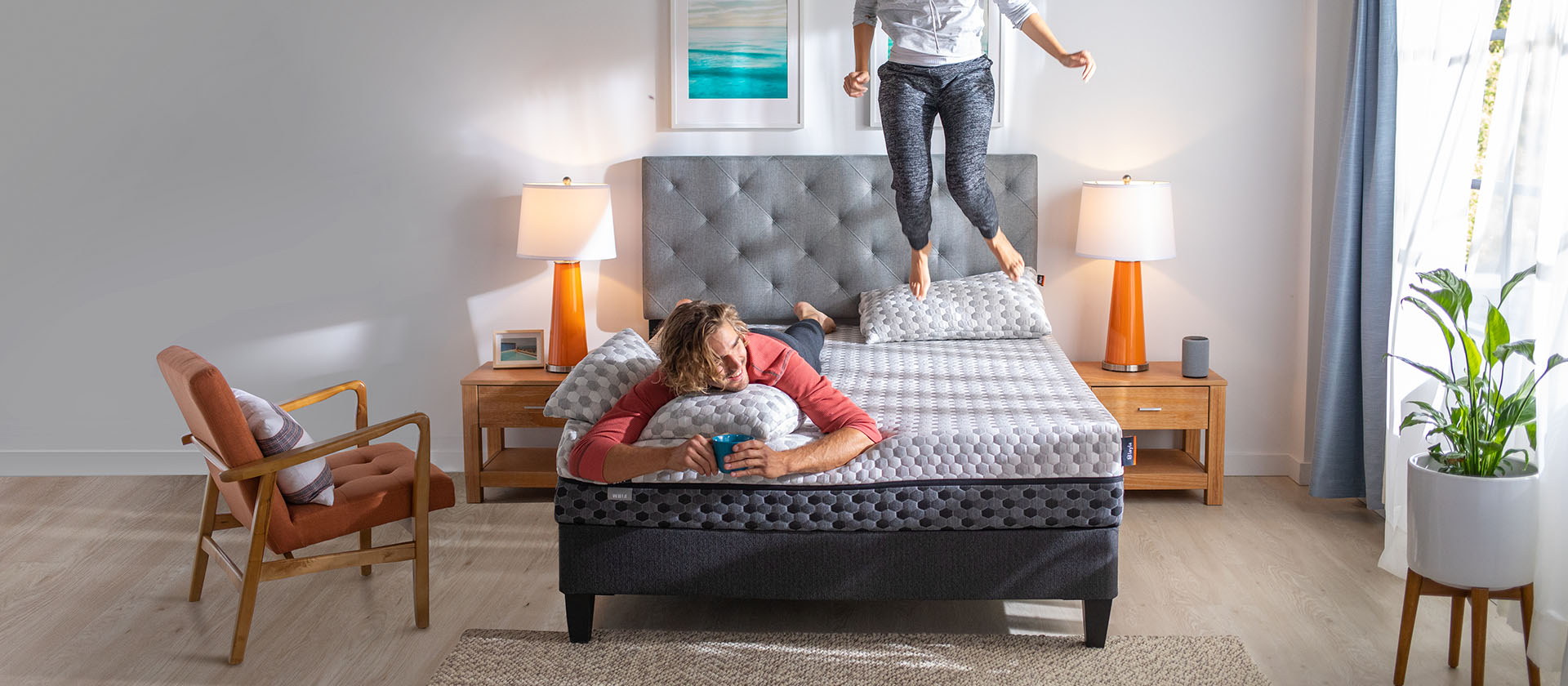 Woman jumping on a bed with man laying on his stomach