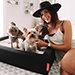 Woman petting 3 dogs on a pet bed