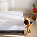 Woman putting the cooling protector on a mattress